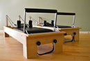 Color image of 2 studio reformers made by Balanced Body. We also use a metal Allegro reformer with a tower attachement.